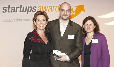 Matt McNeill holding the Innovative Business of the Year award on stage, between Adrienne Lawler and Alison Dwyer